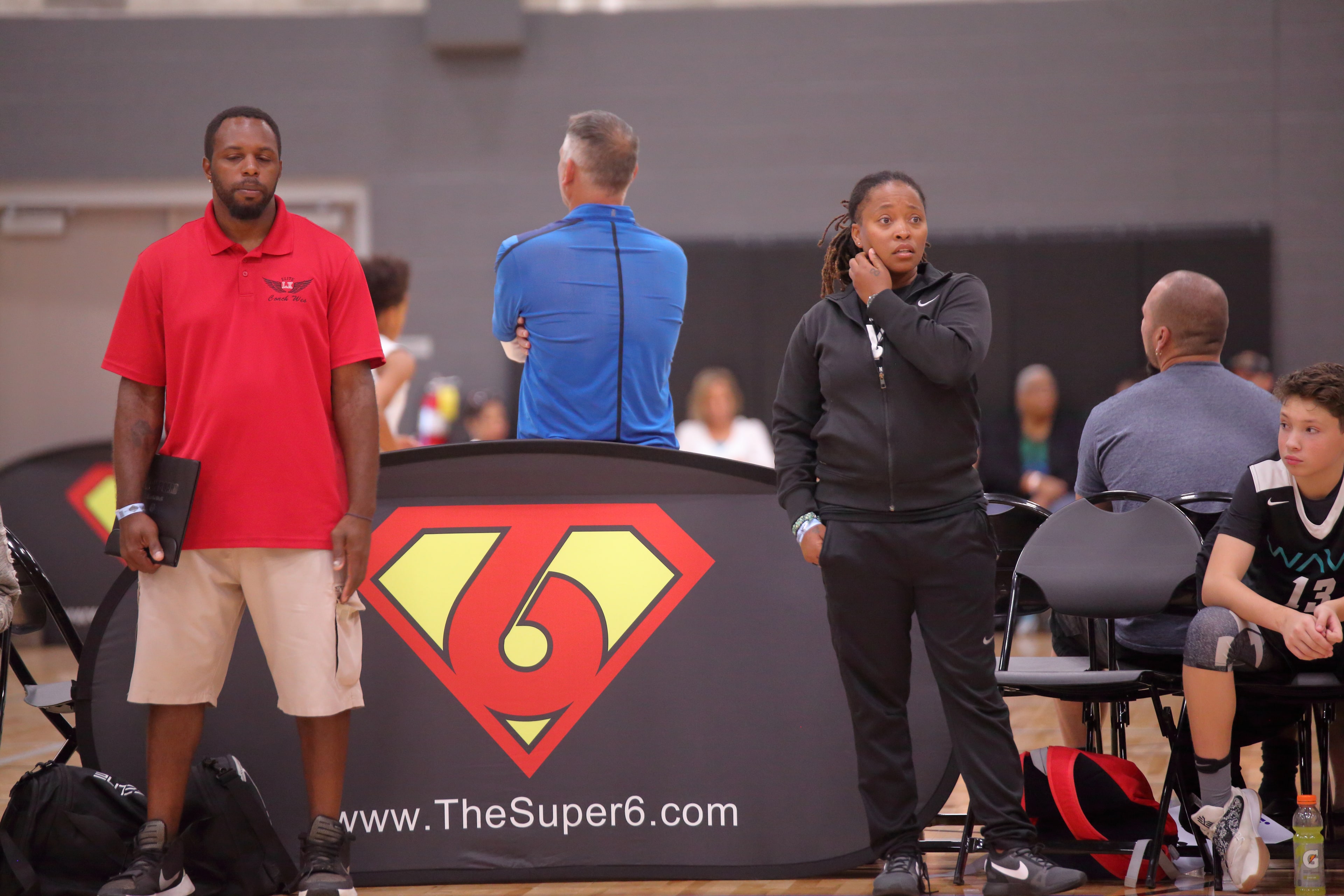 Two coaches standing in front of a Super6 brand wall