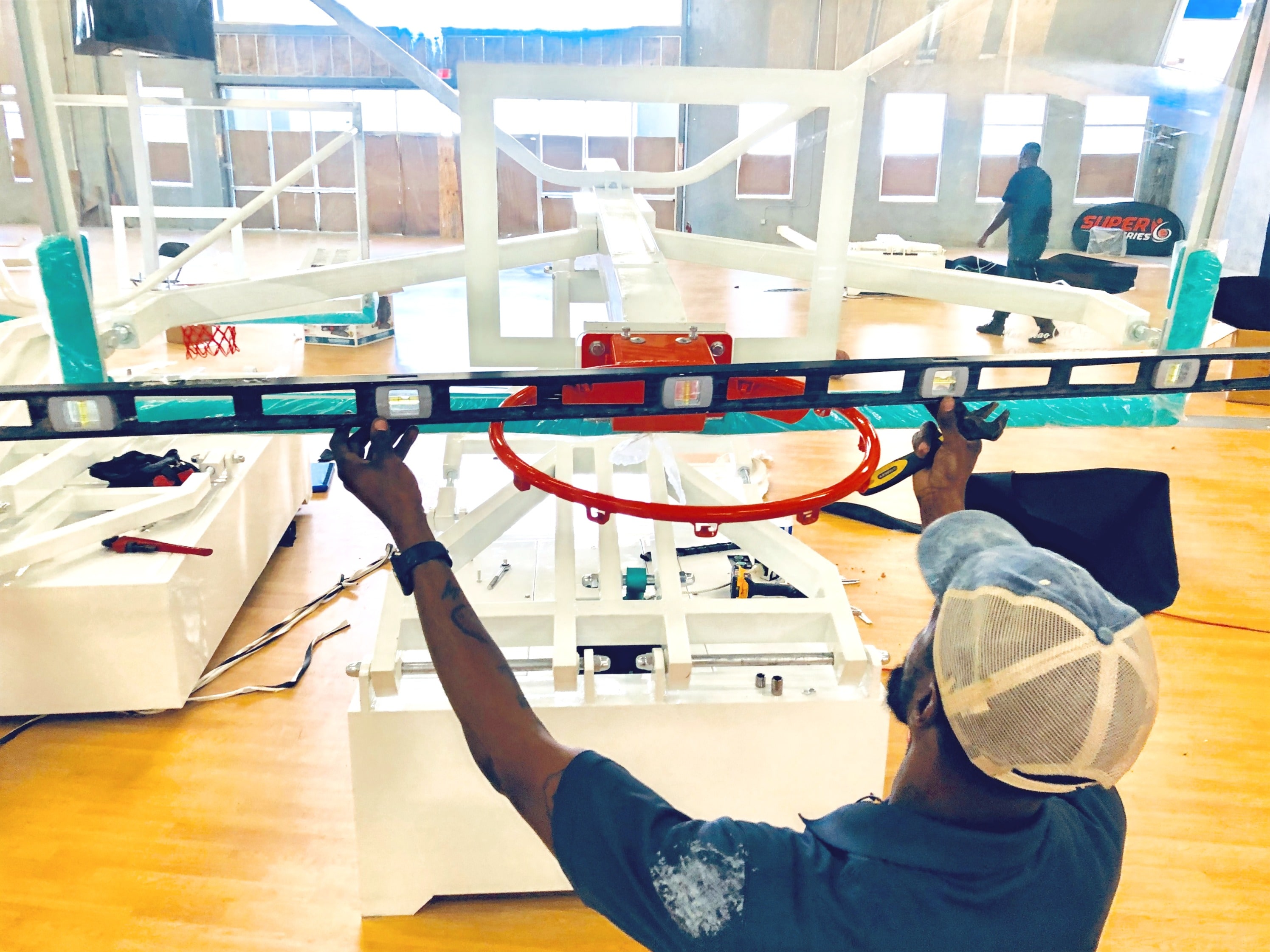 Crew member assembling a professional basketball backboard during venue construction