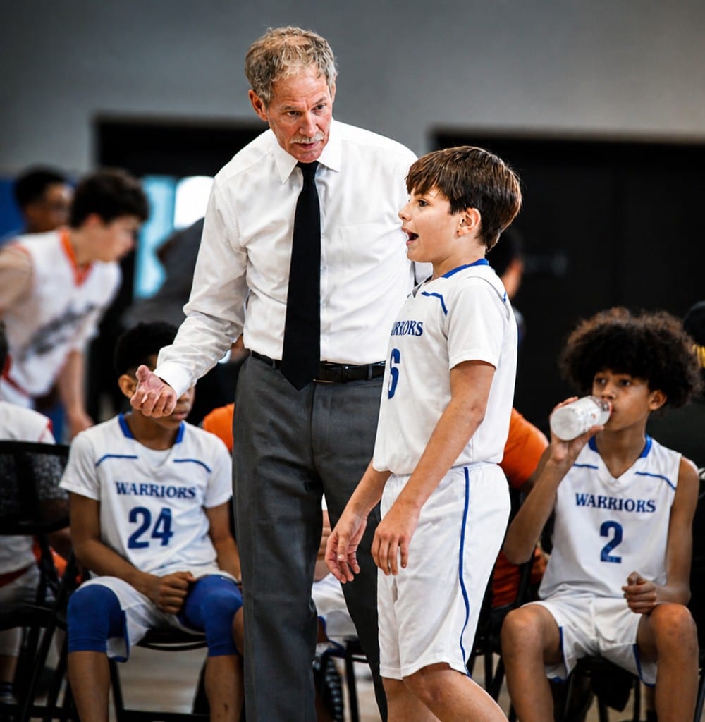 Coach talking with a youth player on the sideline during a game