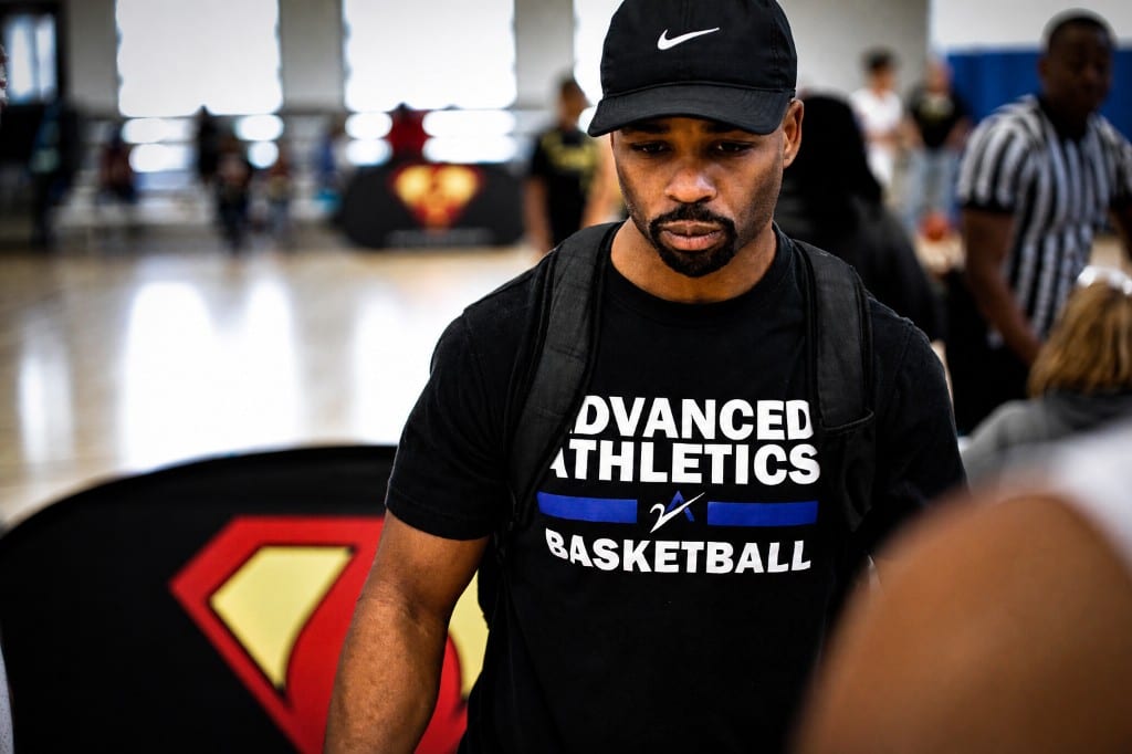 Coach in a basketball gym wearing team apparel near the court