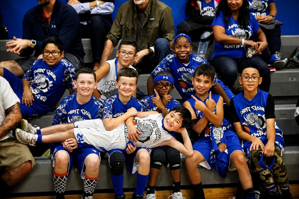 Youth basketball teammates posing together on gym bleachers